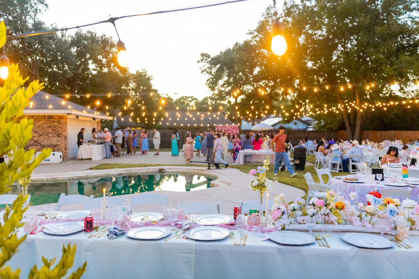 Sacramento backyard graduation party at dusk with permanent outdoor LED lights on the roofline displaying school colors over a decorated dinner table