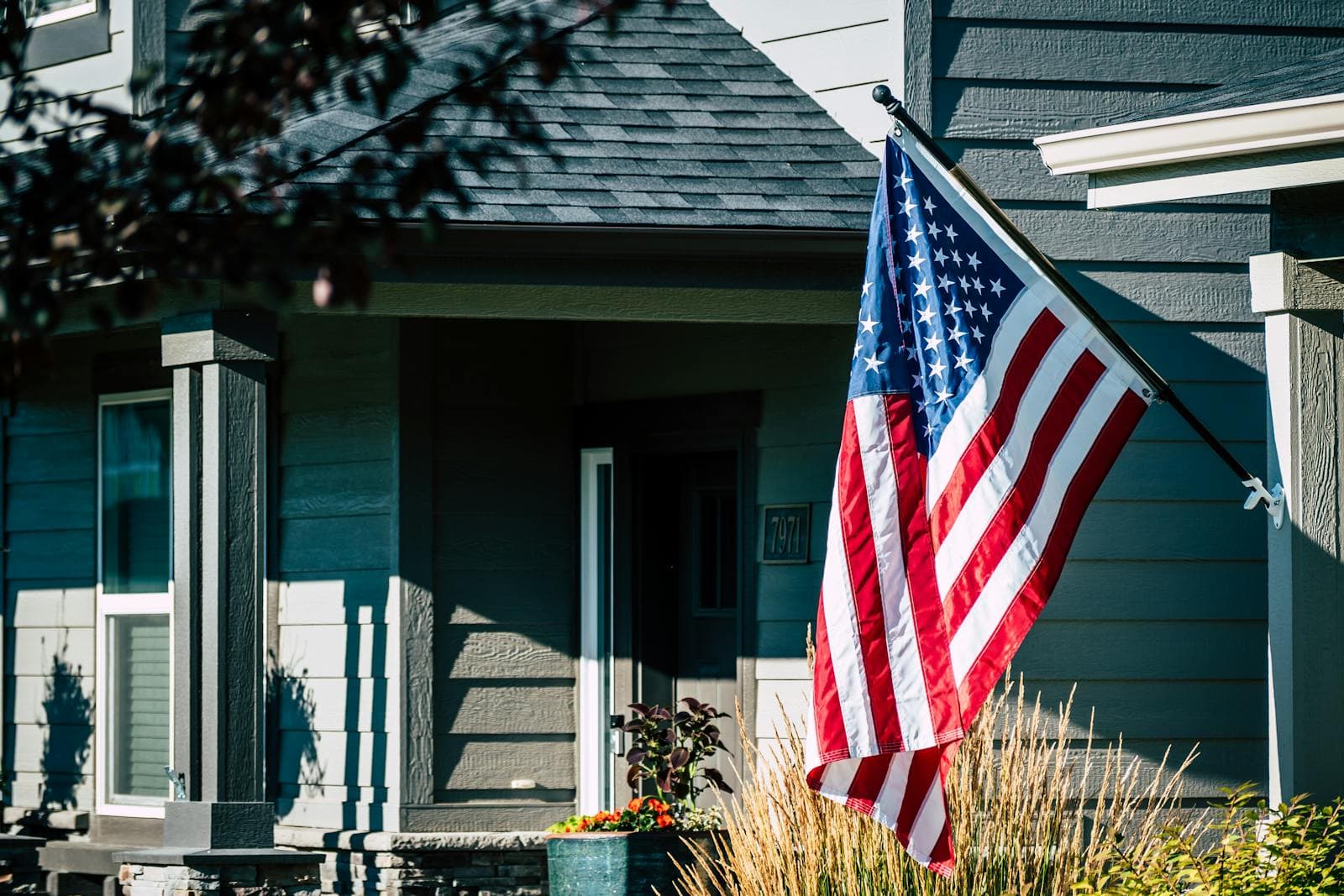 Sacramento home with permanent outdoor LED lights along the roofline programmed in red, white, and blue for Memorial Day weekend, with an American flag visible at twilight — patriotic exterior lighting for the 2026 semiquincentennial