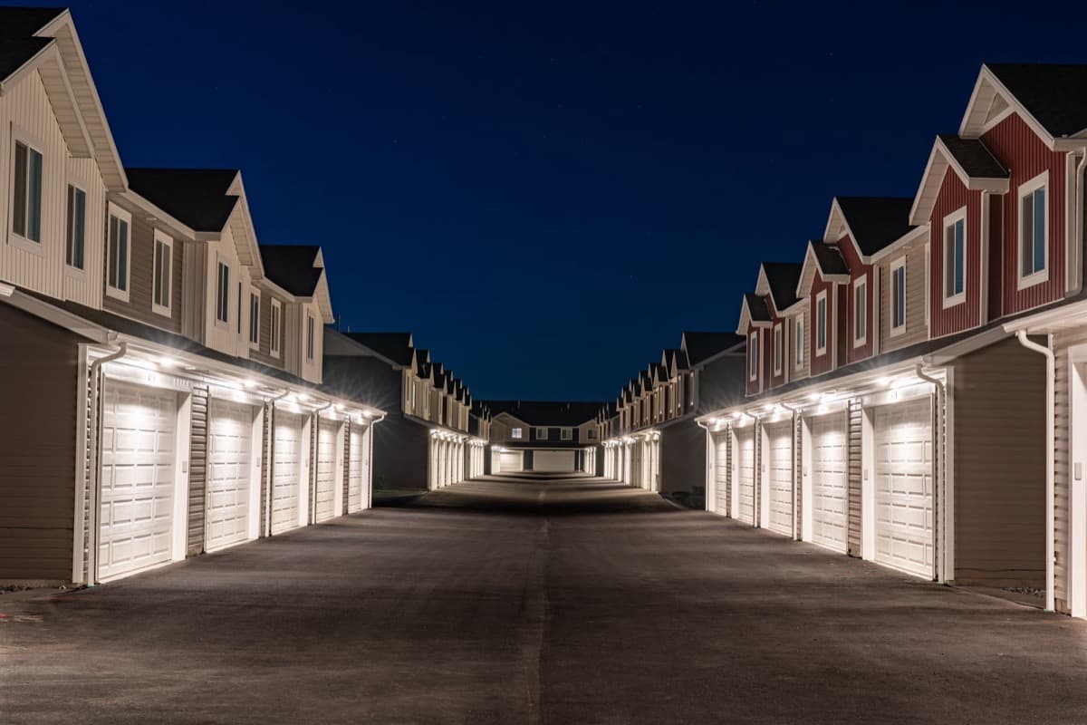 Sacramento townhome apartment community at night with permanent LED lighting illuminating garage rooflines and the shared drive aisle