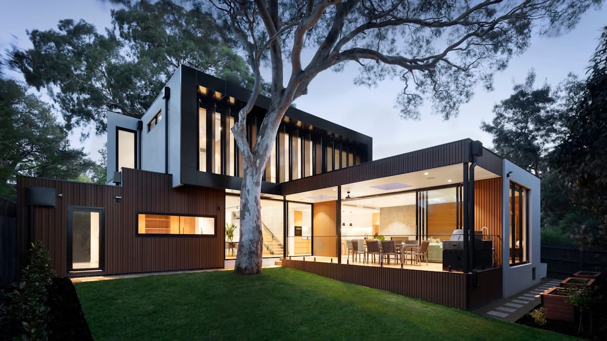 Sacramento home entrance with permanent LED lights illuminating stone pillars, wrought iron gate, and fence line at dusk, creating warm curb appeal beyond the roofline