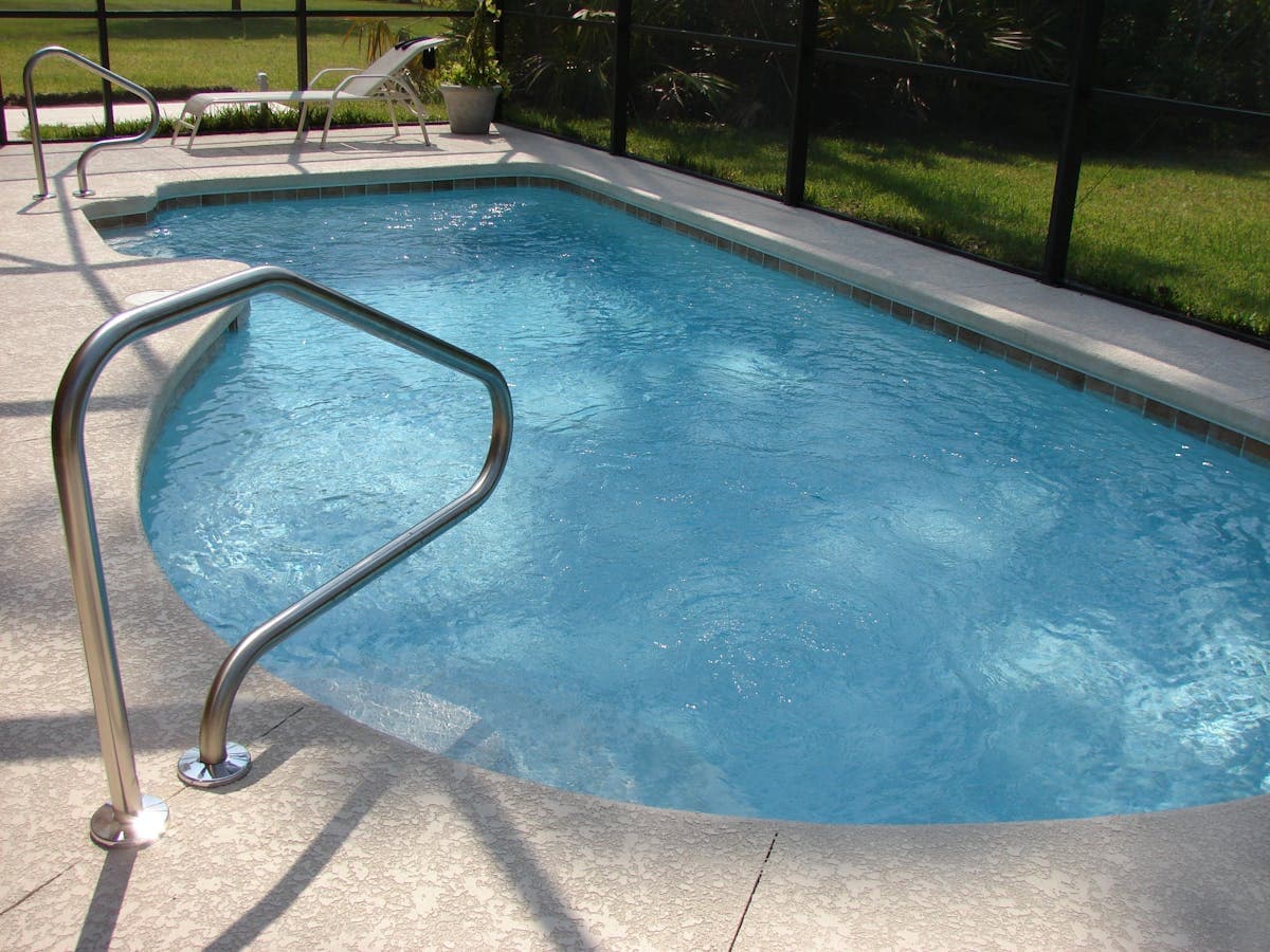Sacramento backyard swimming pool illuminated at night with permanent LED outdoor lights mounted on the pool house and surrounding structures