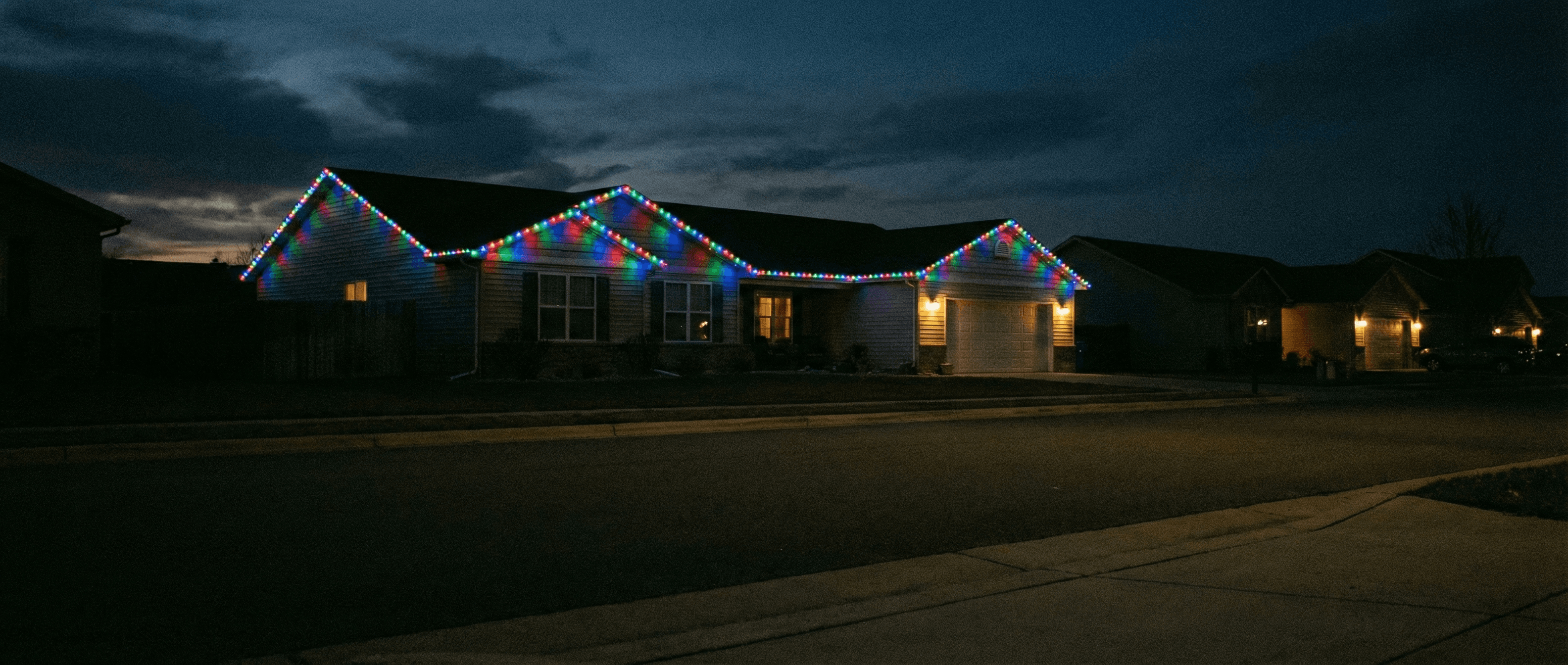 Large ranch with festive multicolor Christmas roofline lighting